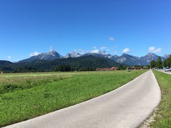 Country road by mountains against sky