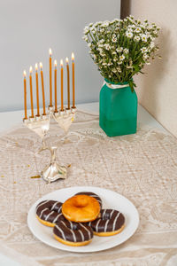 Menorah candles with donuts on table