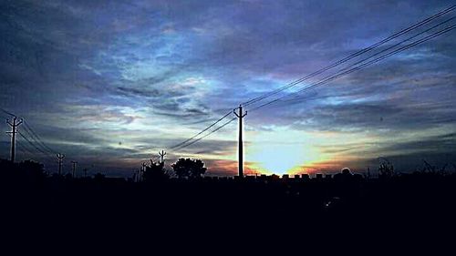 Silhouette electricity pylon against sky during sunset