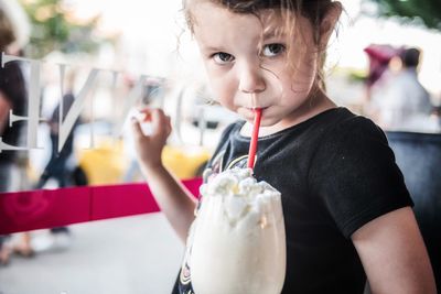 Portrait of girl sucking coffee in city