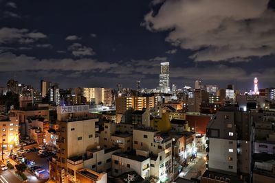 View of city lit up against cloudy sky