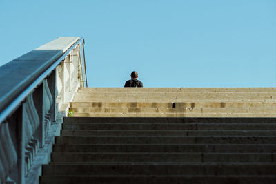 Low angle view of man on staircase against clear sky