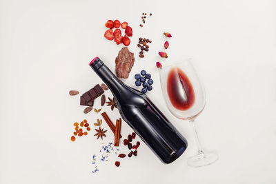 Creative composition with wine bottle, glass and possible flavor components of red wine.