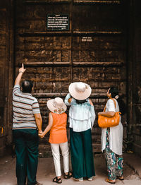 Rear view of people standing against built structure