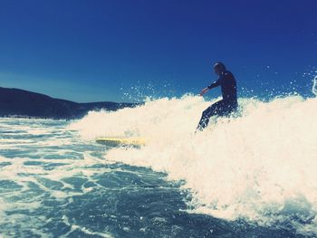 Man surfing in sea against clear sky