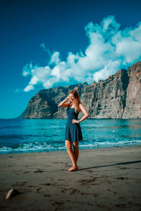 Woman standing at beach against sky