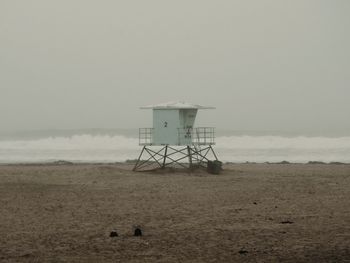 Lifeguard hut on sand at beach against sky