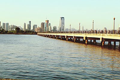 Bridge over river by buildings against sky in city