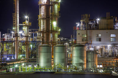 Illuminated factory against sky at night