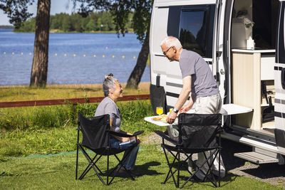 Senior couple having meal by camper van