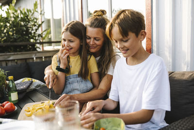 Smiling mother cutting vegetable on table in balcony