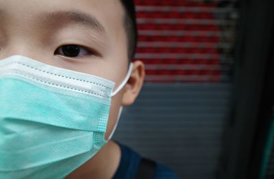 Close-up of boy wearing flu mask outdoors
