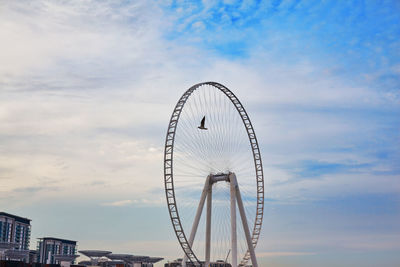 A bird flies against the backdrop of the eye of dubai ferris wheel on bluewater island, travel