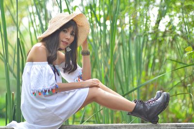 Young woman wearing hat sitting on plants