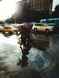 Reflection of man working on wet puddle in city
