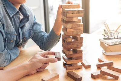 Male friends playing block removal game on table