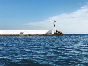 Lighthouse by sea against sky