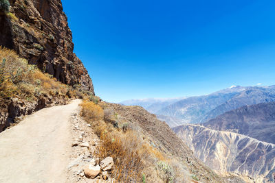 Road on mountain against clear blue sky 