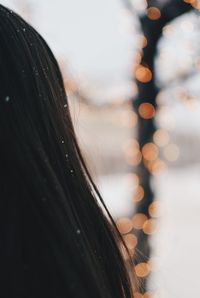 Close-up yo the hair of a woman with snow flakes and christmas lights