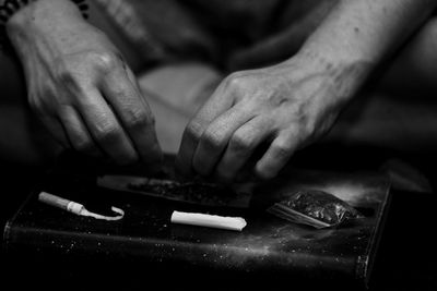 Cropped image of woman rolling marijuana joint on table