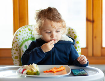 Girl eating food while sitting on table