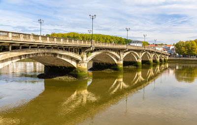 Arch bridge over river against sky