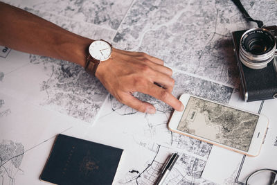 Cropped image of hand using phone over world map by camera