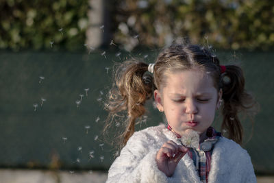 Cute girl blowing dandelion outdoors