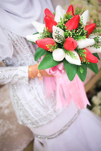 Midsection of bride holding bouquet