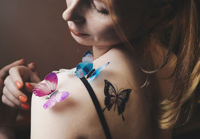 Close-up of woman with artificial butterflies on shoulder