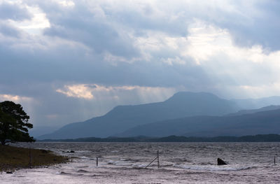 Scenic view of sea by mountains against sky