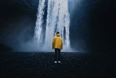 Rear view of man standing against waterfall