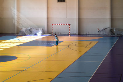 Side view of woman cleaning basketball court