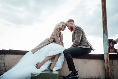 Rear view of couple kissing against sky