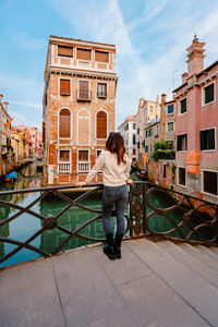 Rear view of woman standing against buildings in city