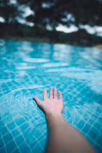 Cropped hand of person by swimming pool