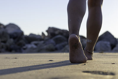 Low section of woman walking on sand at beach