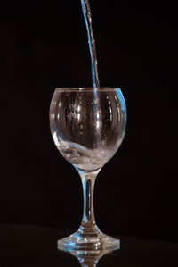 Close-up of wineglass on table against black background