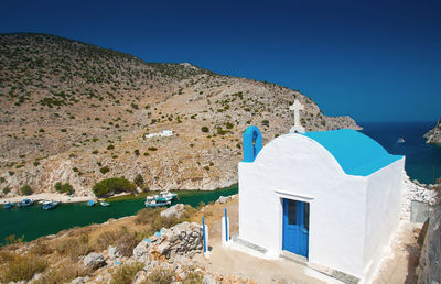 Chapel by sea against clear blue sky