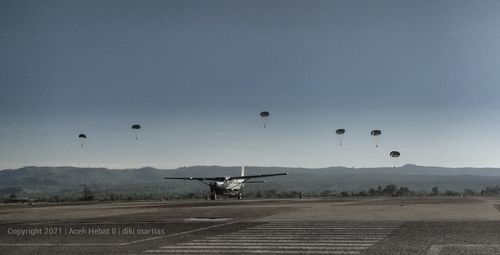 Airplane flying over airport runway against sky