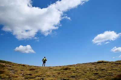 Rear view of man standing on landscape against sky