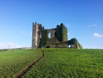 Old ruins on field against blue sky