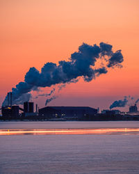 Smoke emitting from factory against sky during sunset