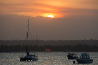 Boat sailing on river against sky during sunset