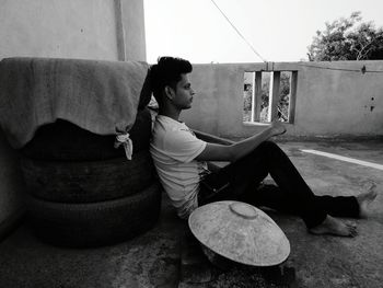 Side view full length of young man sitting on terrace