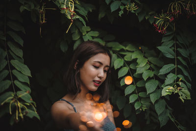 Portrait of young woman standing against plants