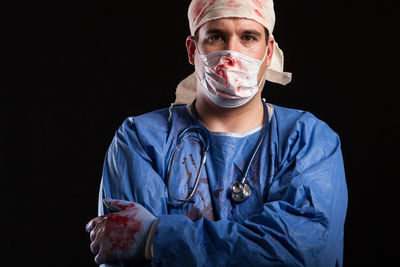 Portrait of man wearing mask against black background