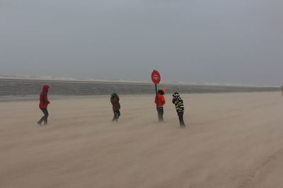 People at beach against sky during storm