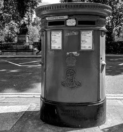 Telephone booth on sidewalk by road in city