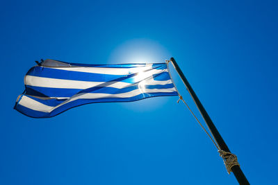 Low angle view of greek flag waving against clear blue sky